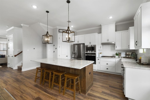 kitchen with appliances with stainless steel finishes, a center island, white cabinetry, backsplash, and hanging light fixtures