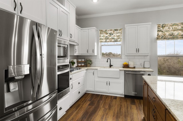 kitchen with sink, dark wood-type flooring, light stone countertops, stainless steel appliances, and white cabinets