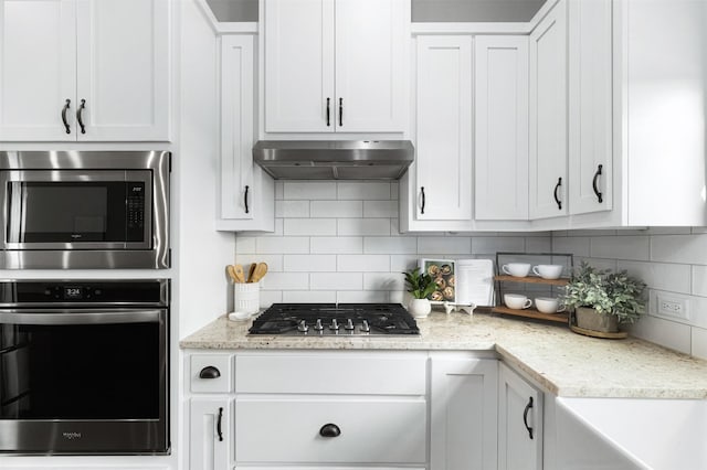 kitchen featuring backsplash, extractor fan, stainless steel appliances, white cabinets, and light stone counters