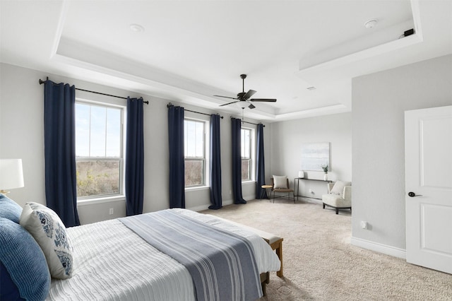 carpeted bedroom featuring ceiling fan and a raised ceiling