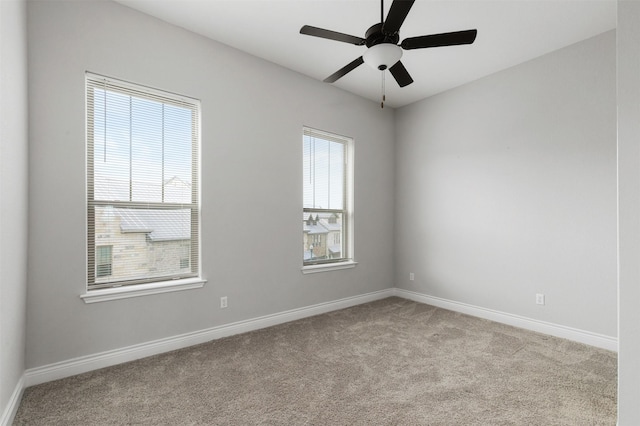 carpeted empty room with ceiling fan and a wealth of natural light