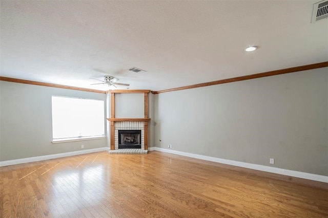 unfurnished living room featuring ceiling fan, light hardwood / wood-style floors, crown molding, and a fireplace