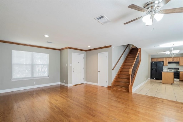 unfurnished living room with ceiling fan with notable chandelier, crown molding, and light hardwood / wood-style flooring