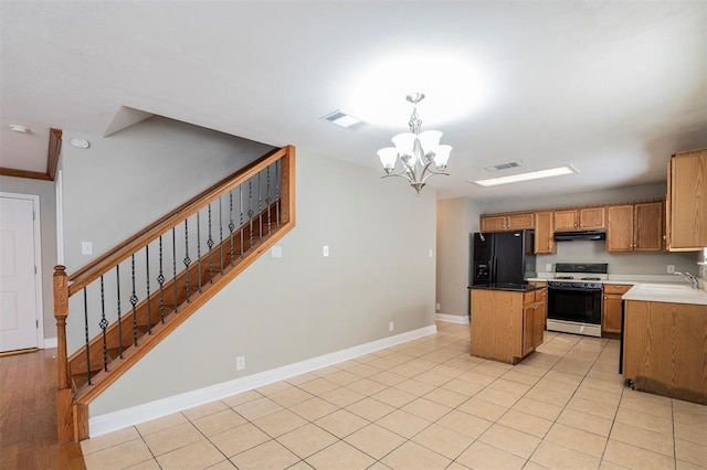 kitchen featuring black refrigerator with ice dispenser, range with gas cooktop, a chandelier, pendant lighting, and a kitchen island