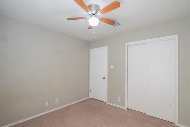 unfurnished bedroom with a closet, light colored carpet, and ceiling fan