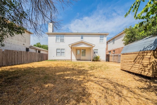 rear view of property with a yard and a storage unit