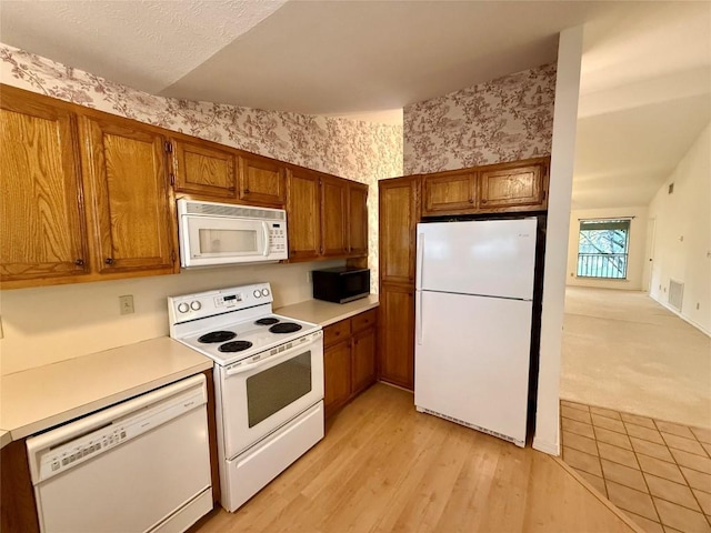 kitchen with white appliances and light hardwood / wood-style flooring