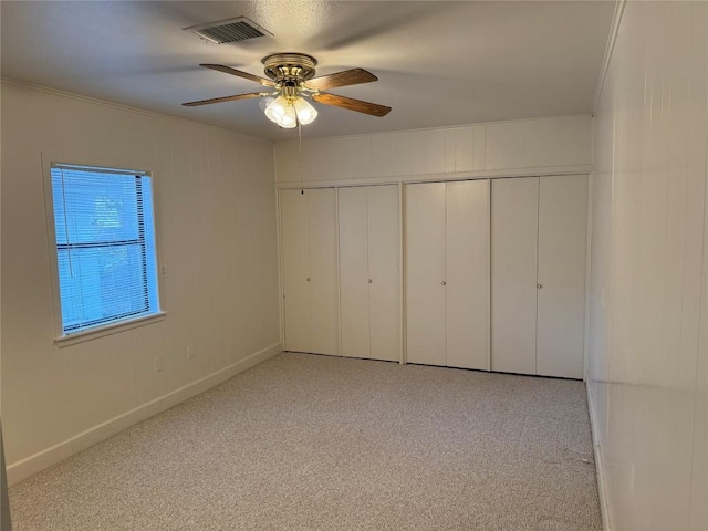 unfurnished bedroom featuring ceiling fan, crown molding, light carpet, and a closet