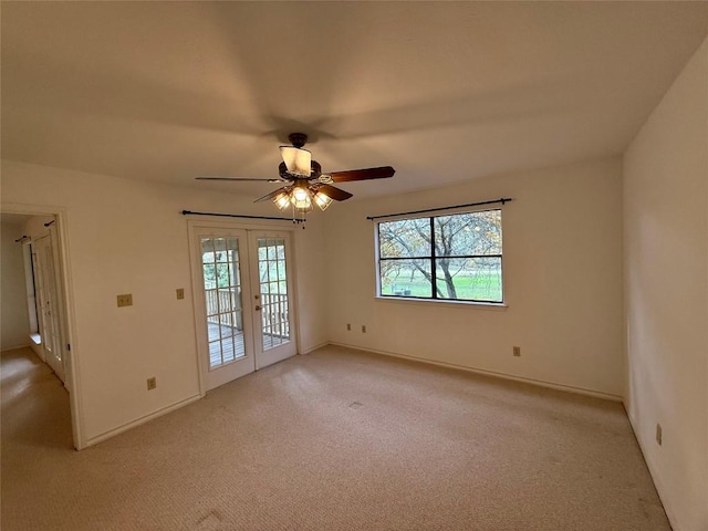 carpeted spare room with ceiling fan and french doors