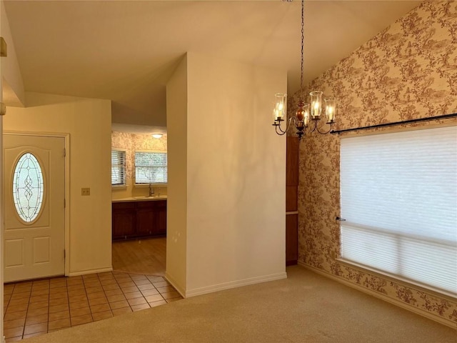 carpeted foyer with lofted ceiling, plenty of natural light, a notable chandelier, and sink