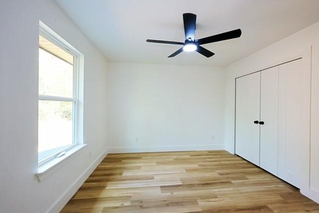 unfurnished bedroom featuring ceiling fan, light hardwood / wood-style floors, and a closet