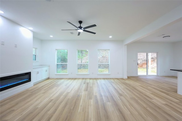 unfurnished living room with light hardwood / wood-style floors, ceiling fan, and a healthy amount of sunlight