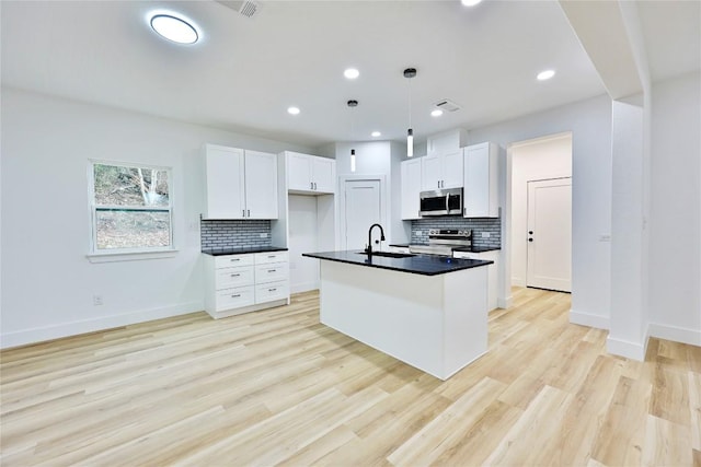 kitchen with white cabinets, appliances with stainless steel finishes, light hardwood / wood-style floors, and pendant lighting