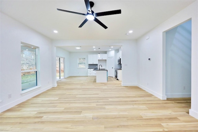 unfurnished living room featuring light hardwood / wood-style floors, ceiling fan, and sink