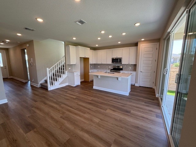 132 Alistair Dr, Georgetown, TX 78633 - kitchen with stainless steel microwave, stove, light countertops, decorative backsplash, and white cabinetry