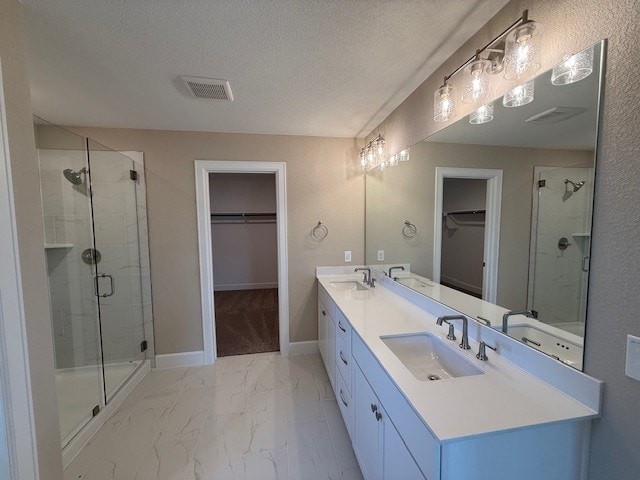 132 Alistair Dr, Georgetown, TX 78633 - full bathroom featuring a spacious closet, double vanity, a stall shower, marble finish floors, and a textured ceiling
