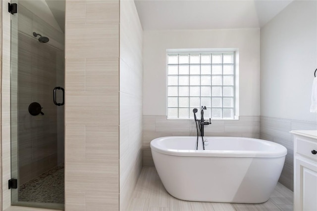504 River Down Rd, Georgetown, TX 78628 - full bathroom featuring tile walls, a shower stall, a soaking tub, vanity, and wainscoting