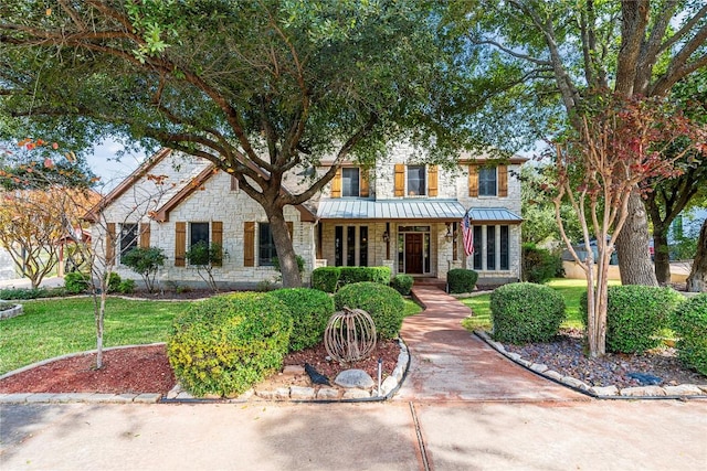 504 River Down Rd, Georgetown, TX 78628 - view of front facade featuring stone siding, a standing seam roof, covered porch, a front lawn, and a metal roof