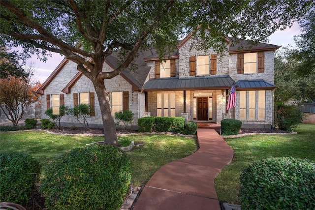 view of front of property with a standing seam roof, a front yard, and stone siding