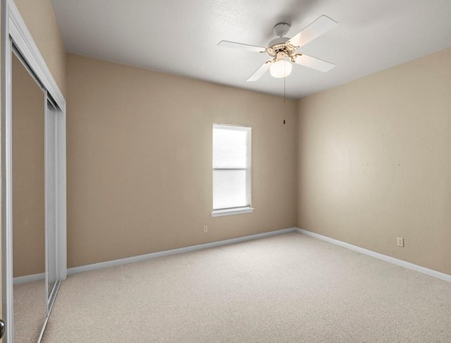 unfurnished bedroom featuring ceiling fan, a closet, and light carpet