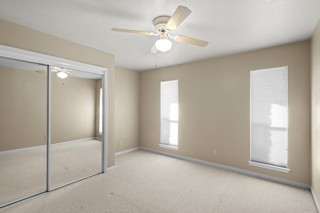 unfurnished bedroom with ceiling fan, a closet, and light colored carpet