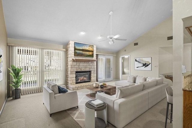 living room featuring high vaulted ceiling, a stone fireplace, ceiling fan, and light colored carpet