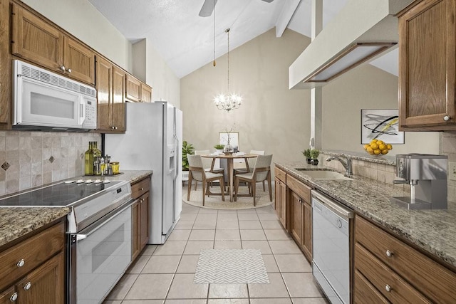 kitchen with white appliances, sink, vaulted ceiling with beams, decorative light fixtures, and light stone counters