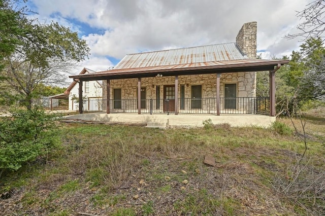 13000 Grubstake Gulch St, Bee Cave, TX 78738 - rear view of property with stone siding, a chimney, a porch, and metal roof