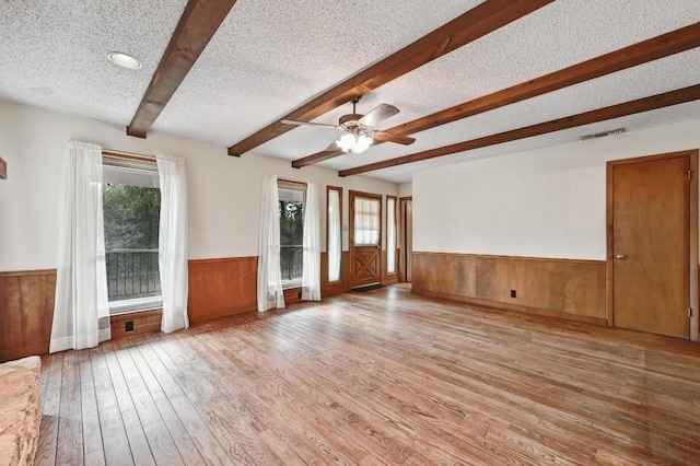 13000 Grubstake Gulch St, Bee Cave, TX 78738 - unfurnished living room with a wainscoted wall, plenty of natural light, wood finished floors, beamed ceiling, and wood walls