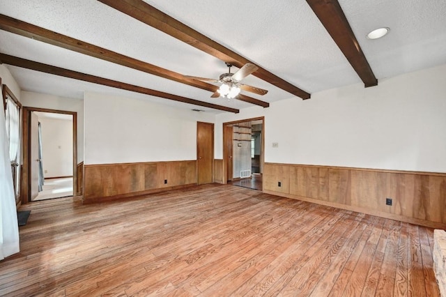 13000 Grubstake Gulch St, Bee Cave, TX 78738 - spare room featuring beamed ceiling, wainscoting, light wood-type flooring, a ceiling fan, and wooden walls