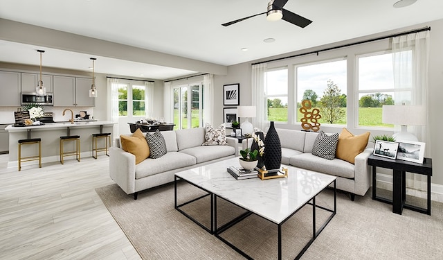 living room with light hardwood / wood-style flooring, ceiling fan, and sink