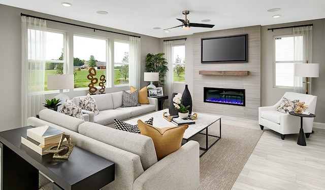 living room with a fireplace, light wood-type flooring, plenty of natural light, and ceiling fan