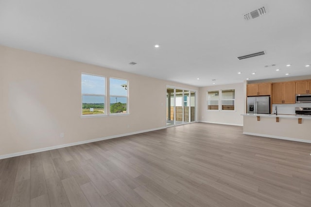 529 Raleigh Dr, Georgetown, TX 78633 - unfurnished living room featuring light wood-style flooring, baseboards, recessed lighting, and a sink