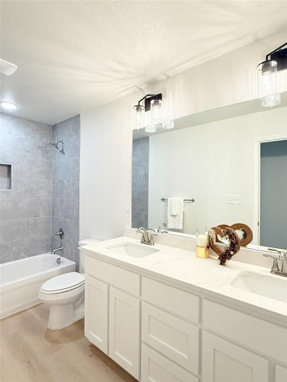 247 Fawn Ridge Dr, Copperas Cove, TX 76522 - bathroom featuring double vanity, wood finished floors, toilet,  shower combination, and a textured ceiling