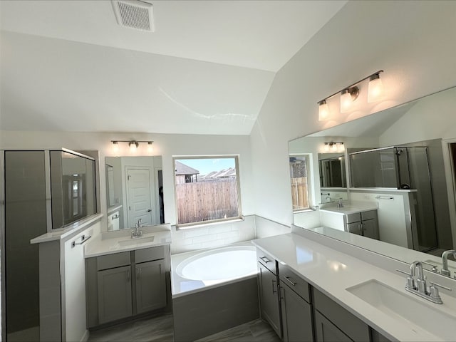 bathroom featuring vaulted ceiling, visible vents, a sink, and a bath