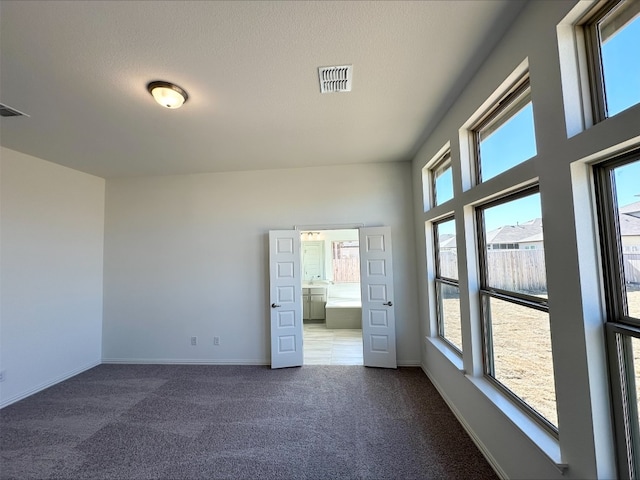 unfurnished room featuring dark carpet, visible vents, and baseboards