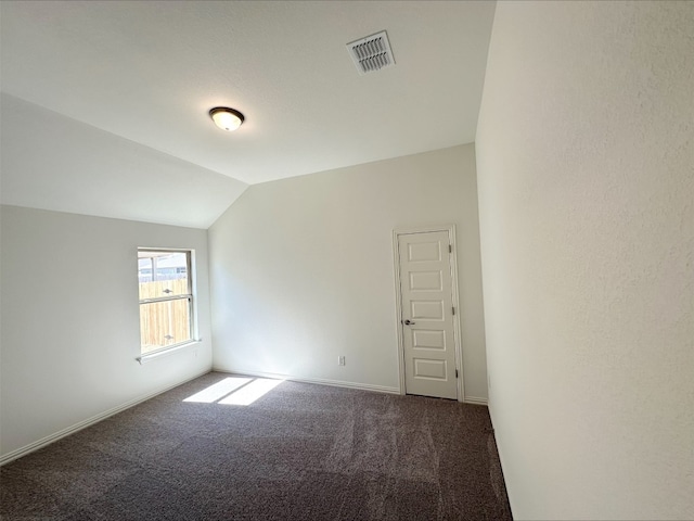 unfurnished room with lofted ceiling, baseboards, visible vents, and dark colored carpet