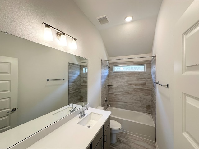 full bathroom featuring visible vents, toilet, vaulted ceiling, vanity, and washtub / shower combination