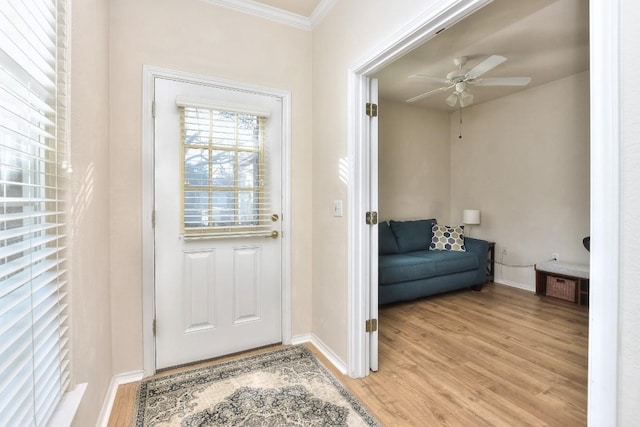 doorway with a ceiling fan, crown molding, light wood-style flooring, and baseboards