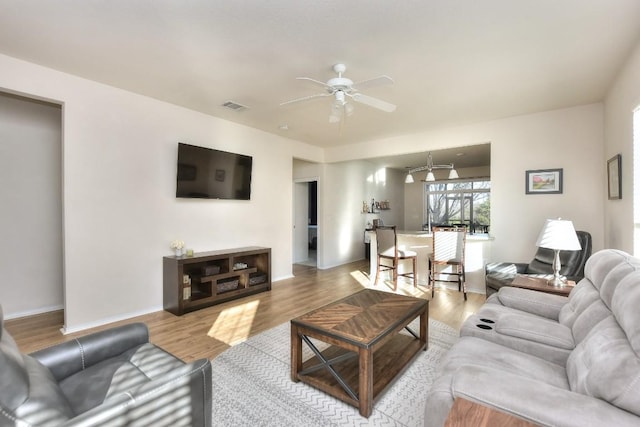 living area featuring visible vents, ceiling fan, baseboards, and wood finished floors