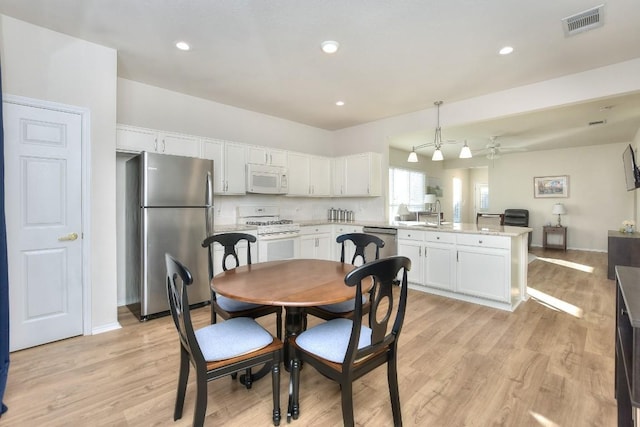 dining space featuring baseboards, light wood-type flooring, visible vents, and recessed lighting