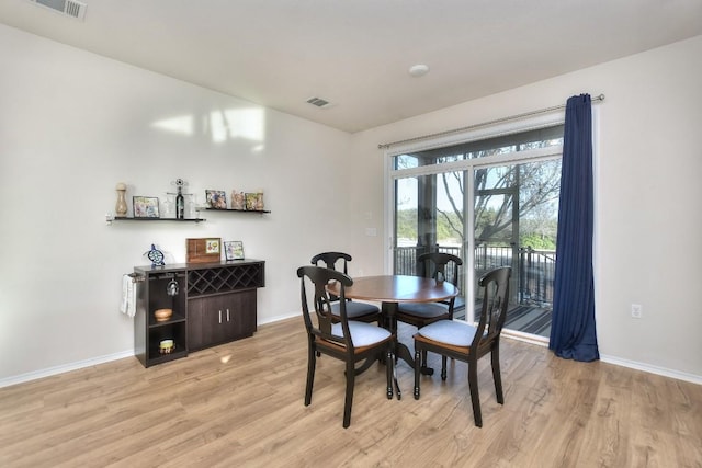 dining space with light wood-type flooring, baseboards, and visible vents