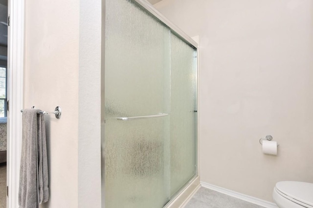 full bathroom featuring baseboards, a shower stall, and toilet