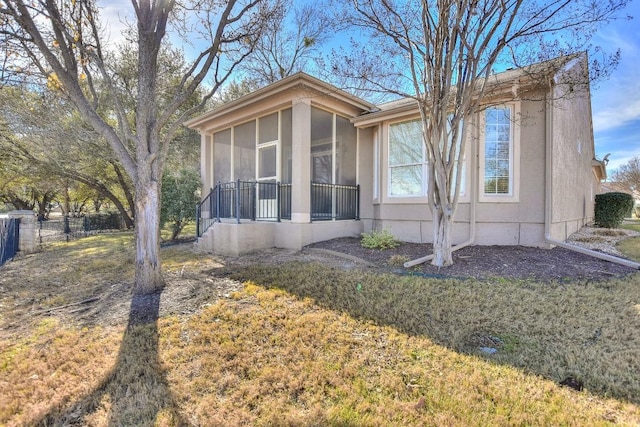 view of side of property with a sunroom, a yard, and fence