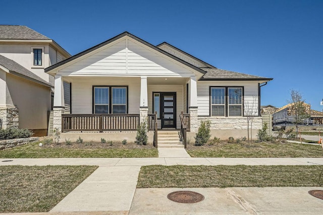 view of front of property featuring covered porch and stone siding