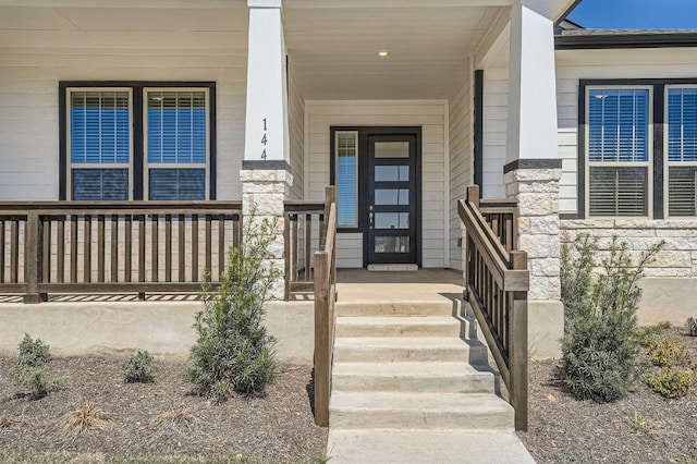 doorway to property with stone siding and a porch