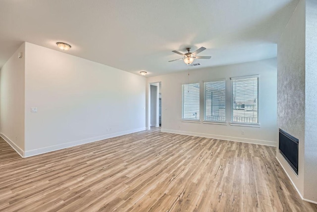 144 Adelton Blvd, Bastrop, TX 78602 - unfurnished living room with a ceiling fan, light wood finished floors, baseboards, and a fireplace