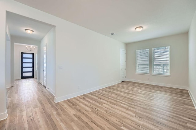 unfurnished room featuring baseboards, visible vents, light wood-style floors, and an inviting chandelier