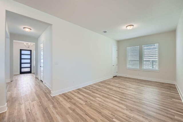 144 Adelton Blvd, Bastrop, TX 78602 - unfurnished room featuring a chandelier, light wood-style floors, and baseboards