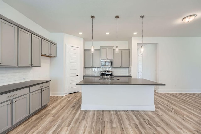 kitchen featuring gray cabinets, light wood-style floors, dark countertops, and appliances with stainless steel finishes
